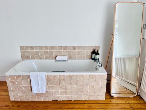 a bath tub in a bathroom next to a mirror at Charming End of Terrace Home with Garden in Cardiff