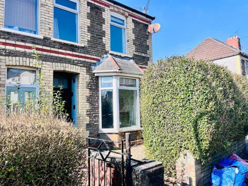 a brick house with two bushes in front of it at Charming End of Terrace Home with Garden in Cardiff