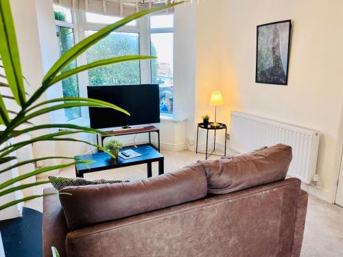 a living room with a brown couch and a plant at Charming End of Terrace Home with Garden in Cardiff