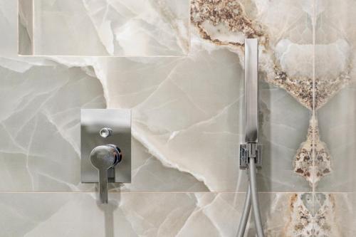 a shower in a bathroom with a marble wall at Cozy studio in the centre in Sitia