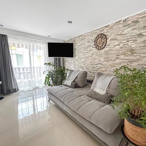 un salon avec un canapé et un mur de briques dans l'établissement Escapade à Nice - T2 cosy, clim & balcon, à Nice