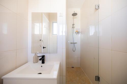 a white bathroom with a sink and a shower at House at the Sea (city historial center with sea view) in Ponta Delgada
