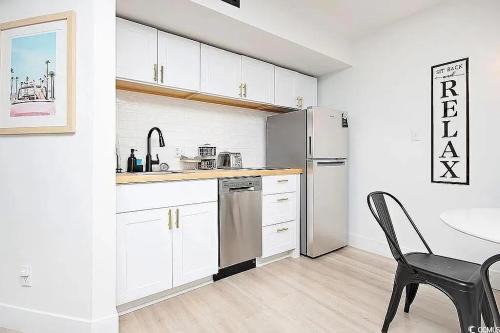 a kitchen with white cabinets and a table and a refrigerator at Coastal Comfort Your Perfect Beachfront Getaway in Myrtle Beach