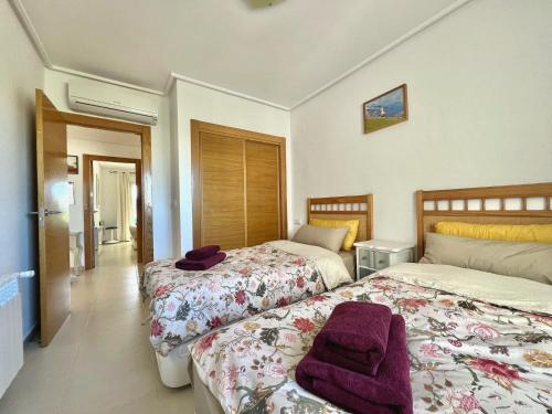 a bedroom with two beds with purple towels on them at Stunning frontline apartment with golf views and pool in Sucina