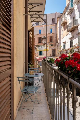 a table on the balcony of a building with flowers at LE PORTE DEL KASSARO in Palermo