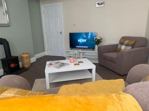 a living room with a tv and a couch and a table at The Hidden Hicks - Sleeps 2 in Whitehaven