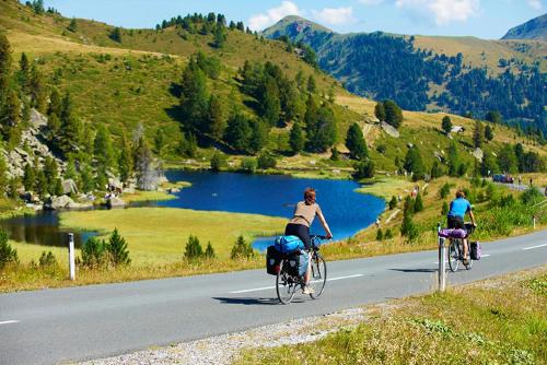 two people riding bikes down a road near a lake at JAUCHZA! Berg Apartments mit 360 Grad Blick in Innerkrems