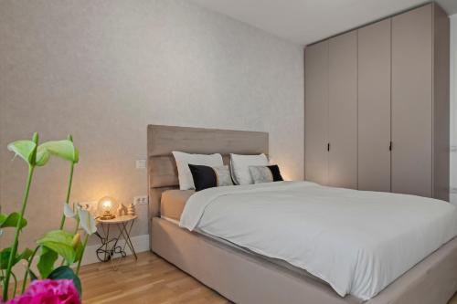 a bedroom with a large white bed and a plant at The Address Bucharest in Bucharest
