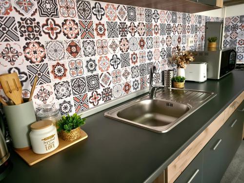 a kitchen counter with a sink and a tile wall at Madalina's House in Braşov