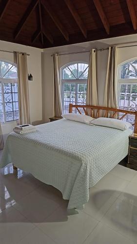 a large bed in a room with two windows at Turquoise Sea Villa in Montego Bay