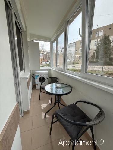 a small table and chairs in a room with windows at Apartamente Felix in Baile Felix