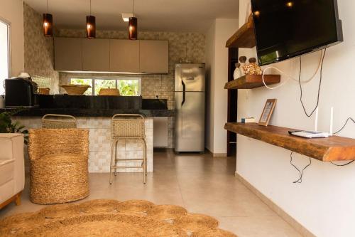 a kitchen with a refrigerator and a counter with chairs at Casa Paradise - Condomínio Bali BG in Barra Grande