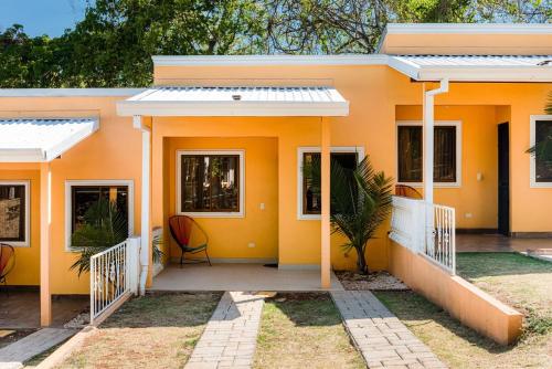 a yellow house with a front porch with a chair at Villa JR 4 near the Guacalillo Rock in Tivives