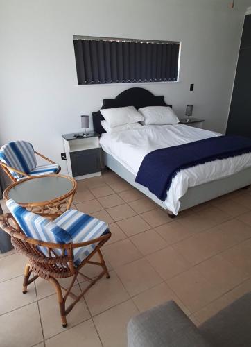 a bedroom with a bed and a chair and a table at Surf Point Ride in Jeffreys Bay