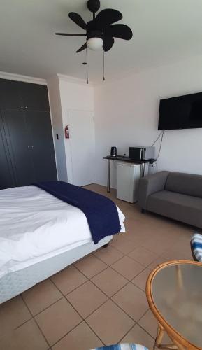 a bedroom with a bed and a couch and a ceiling fan at Surf Point Ride in Jeffreys Bay