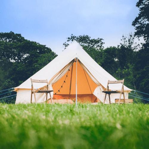 une grande tente avec deux chaises dans un champ dans l'établissement Le Jardin Prive - Glamping de Vivoin, à Vivoin