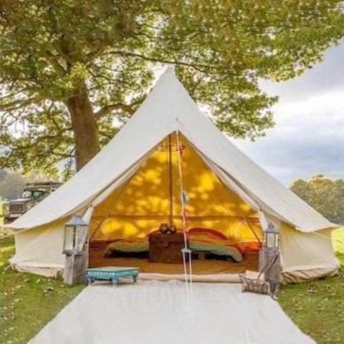 une tente blanche avec un lit dans un champ dans l'établissement Le Jardin Prive - Glamping de Vivoin, à Vivoin