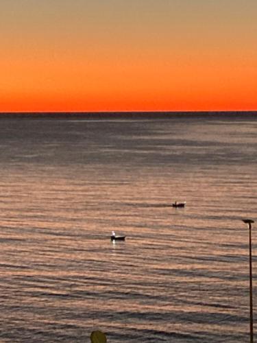 two boats in the water at sunset at Sea-front loft in Liberty villa in Castiglioncello