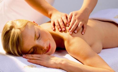 a woman laying on a bed with her hands on her back at AlmDorf Tonnerhütte in Mühlen
