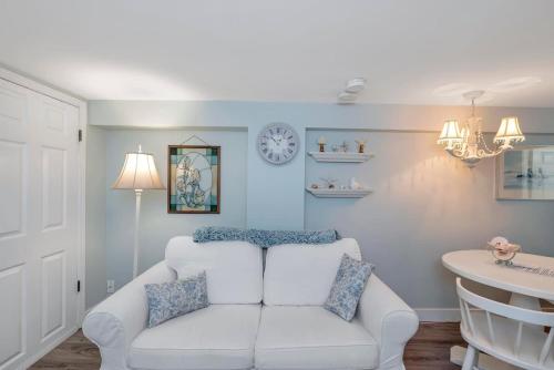 a living room with a white couch and a clock on the wall at Quaint 1 bedroom lower suite in Victoria, BC in Victoria