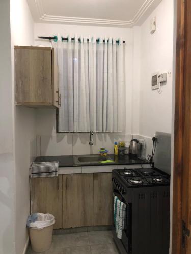 a small kitchen with a stove and a sink at Bliss Residence Bamburi Mwembeni in Mombasa