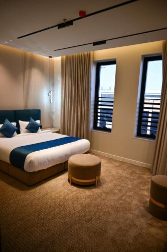 a bedroom with a large bed and two windows at جوهرة العليا للشقق المخدومة in Tabuk