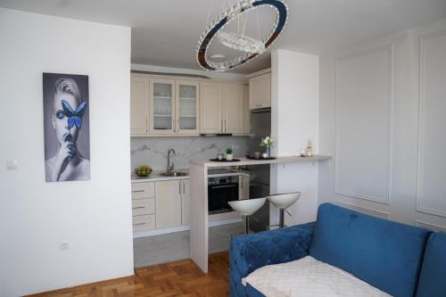 a living room with a blue couch and a kitchen at Apartman Iskra in Bijeljina
