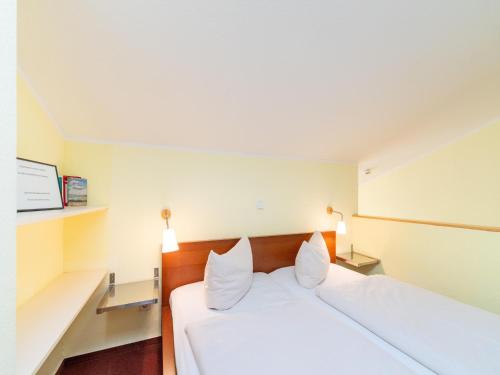 a hotel room with a white bed with two pillows at Unvergessliches Apartment am See in Granzow