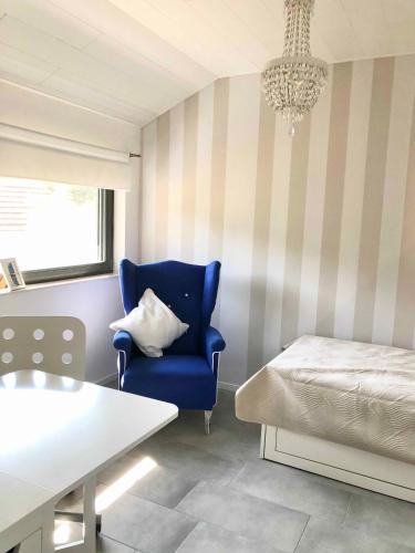 a bedroom with a blue chair and a bed and a chandelier at Apartment mit Blick ins Grüne in Mitterfels