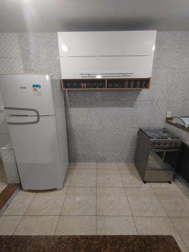 a kitchen with a white refrigerator and a stove at Apto com Garagem - PENHA in Rio de Janeiro