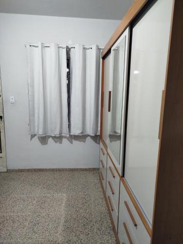 a bathroom with a dresser and a window with curtains at Apto com Garagem - PENHA in Rio de Janeiro