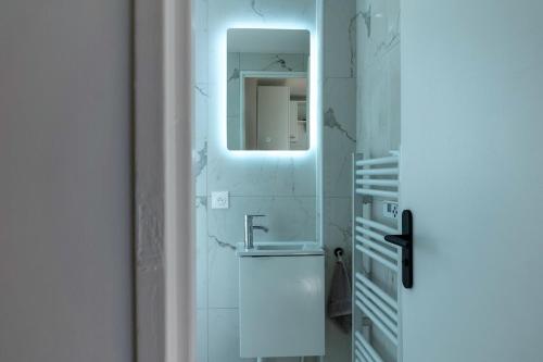 une salle de bain blanche avec un lavabo et un miroir dans l'établissement Little Sacré-Coeur Nest !, à Paris