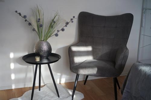 a chair and a table with a vase of flowers on it at Ruheoase mitten in der Stadt in Pirmasens