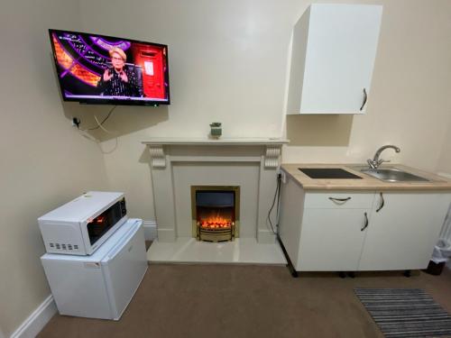 a kitchen with a fireplace with a tv on the wall at The Green Light House Studio 24 - Free Private Parking in Portsmouth