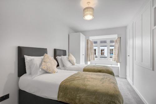 two beds in a bedroom with white walls at The Tanner's Lodge - North East Escapes in Hexham