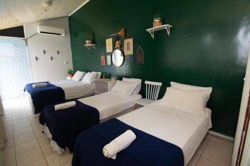 a room with three beds and a green wall at Happiness House Hospedagem in Cuiabá