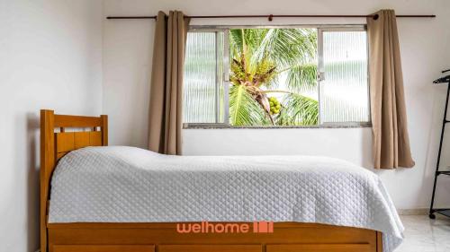 a bedroom with a bed and a window with a palm tree at Casa ampla com lazer completo na Regiao dos Lagos in São Pedro da Aldeia