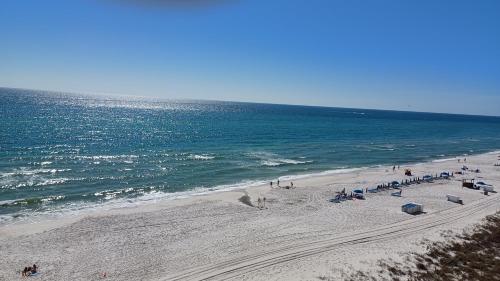a group of people on a beach near the ocean at COUPLES GETAWAY, HONEYMOON SWEET, Perfectly Cozy Beach Front Condo with kitchen, pool, free parking,CHECK-IN AT DOOR in Panama City Beach