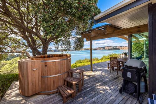 a wooden deck with a hot tub and a grill at The Sanctuary Couples Retreat in Waiheke Island