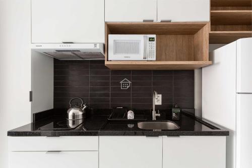 a kitchen with a sink and a microwave at Apartamento completo localizado em um dos melhores bairros de Porto Alegre. in Auxiliadora
