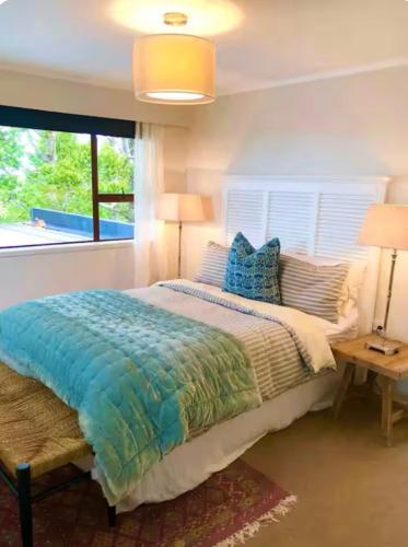 a bedroom with a bed and two lamps and a window at Villa Del Mar Seaside Escape in Orewa