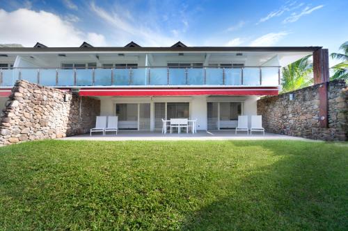 a house with a patio and a stone wall at Moorea Sunset Beach in Haapiti