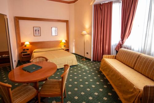 a hotel room with a bed and a couch and a table at Hotel Estense in Modena