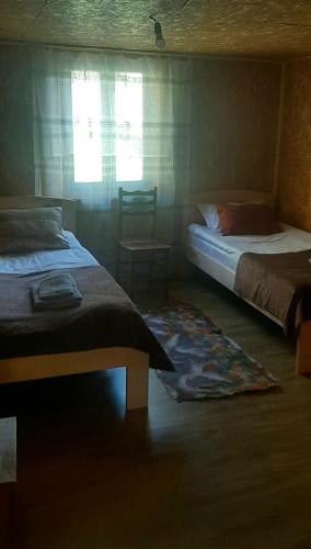 a bedroom with two beds and a window and a rug at Guesthouse hegho სასტუმრო ჰეღო in Omalo
