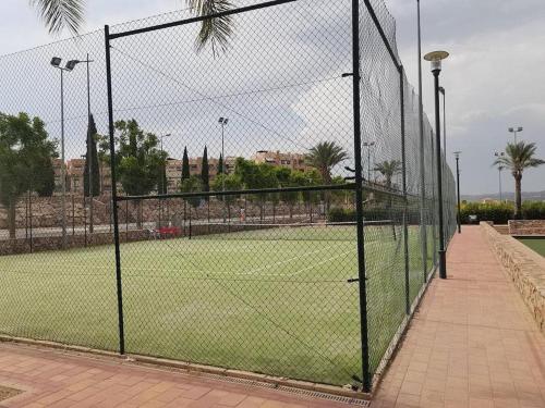 a tennis court behind a chain link fence at Apartamento Leticia in La Tercia