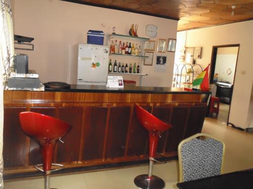 a bar with red stools and a refrigerator at Wli Water Heights Hotel in Wli Afegame