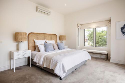 a white bedroom with a large bed and a window at Maori in Rye walk to the beach and shops in minutes in Rye