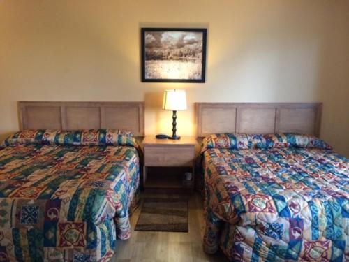 a hotel room with two beds and a table with a lamp at Carleton Motel and Coffee Shop in Borden-Carleton