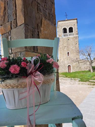 a green chair with flowers on it with a tower at Hiša Skala Kubed in Gračišče
