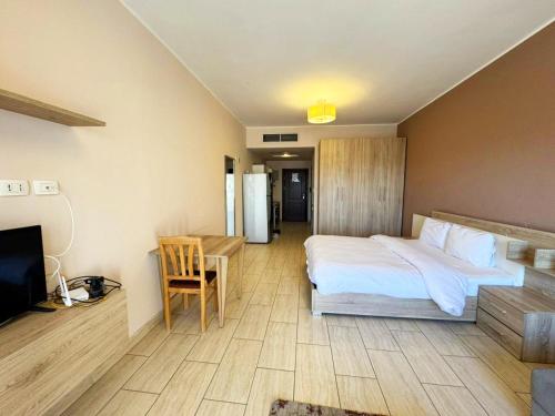een slaapkamer met een bed, een bureau en een televisie bij Apartment Aldau in Hurghada